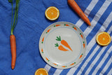 Set 4 piatti And Nook Vegetables in ceramica decorata con illustrazioni di verdure colorate come carote, ravanelli, mais e peperoni, diametro 22 cm.